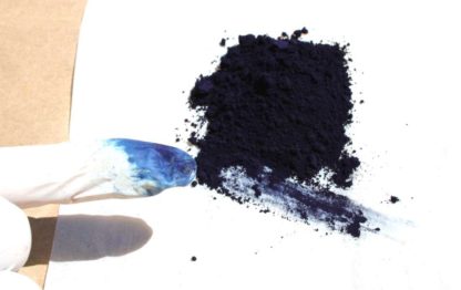 Indigo pigment shown as a pile and smeared on a finger